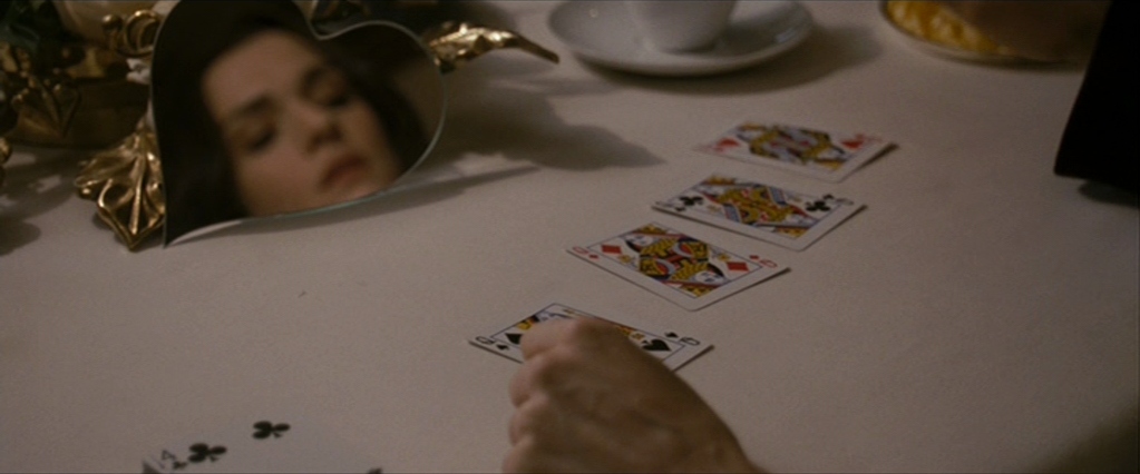 Penelope performs a card trick for Bloom, four queens face up on the table.